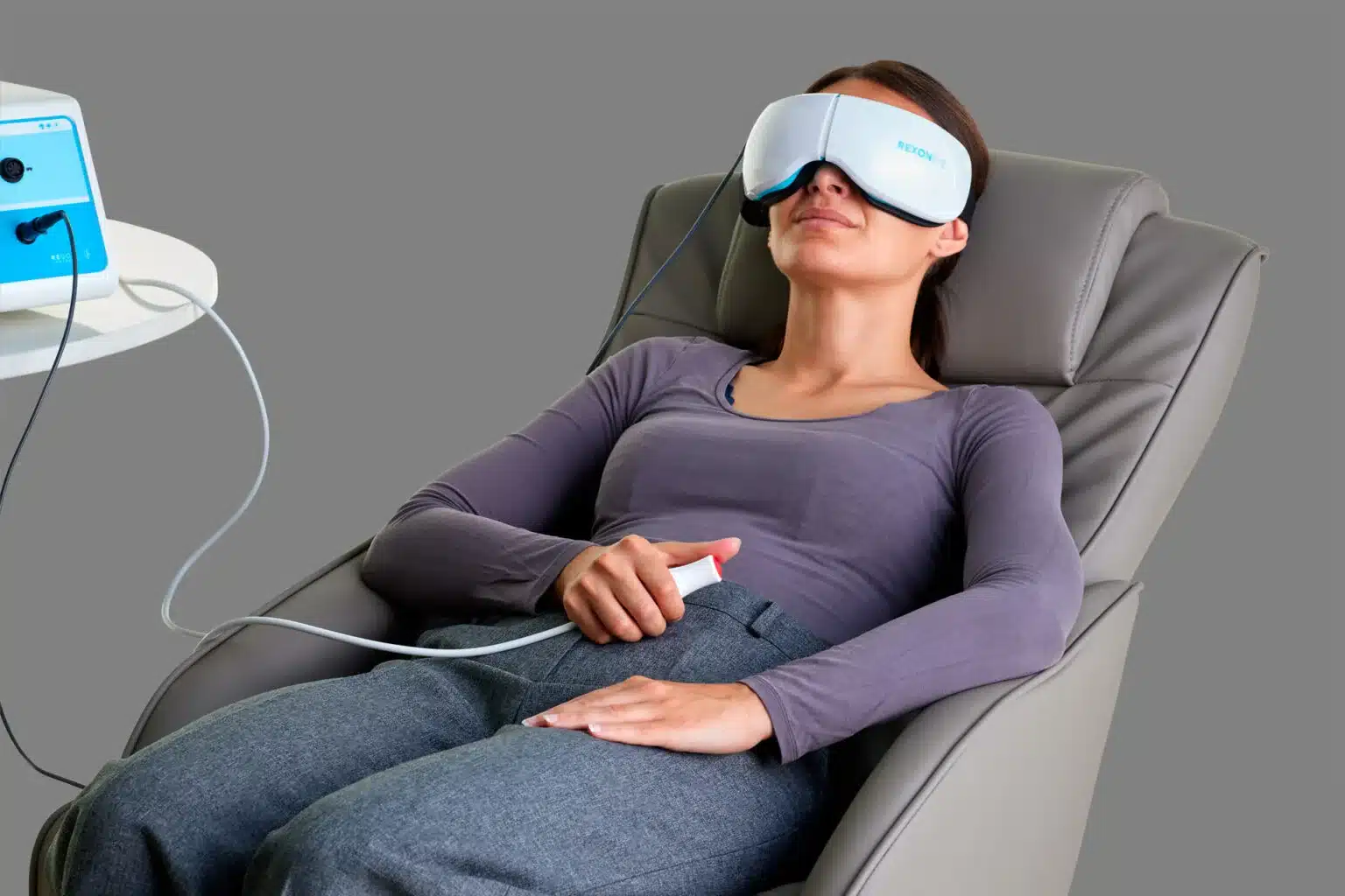 RexonEye Behandlungssystem: liegende Patientin mit Augenmaske und Handcontroller zur Behandlung von Dry Eye